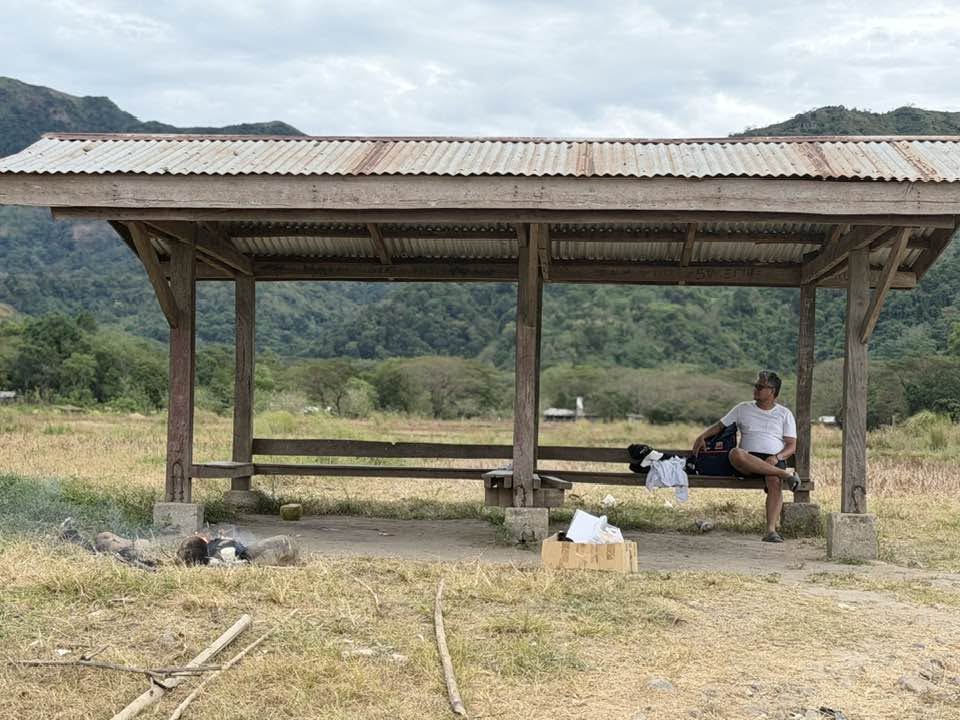 A quiet outdoor scene with Rovic Cruz seated in a rural shelter